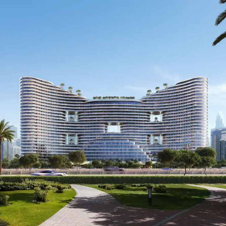 A modern, curved high-rise building with balconies and rooftop greenery, inspired by Binghatti Aquarise, stands amid a landscaped park with palm trees under a clear blue sky. A tall skyscraper rises in the distant background.