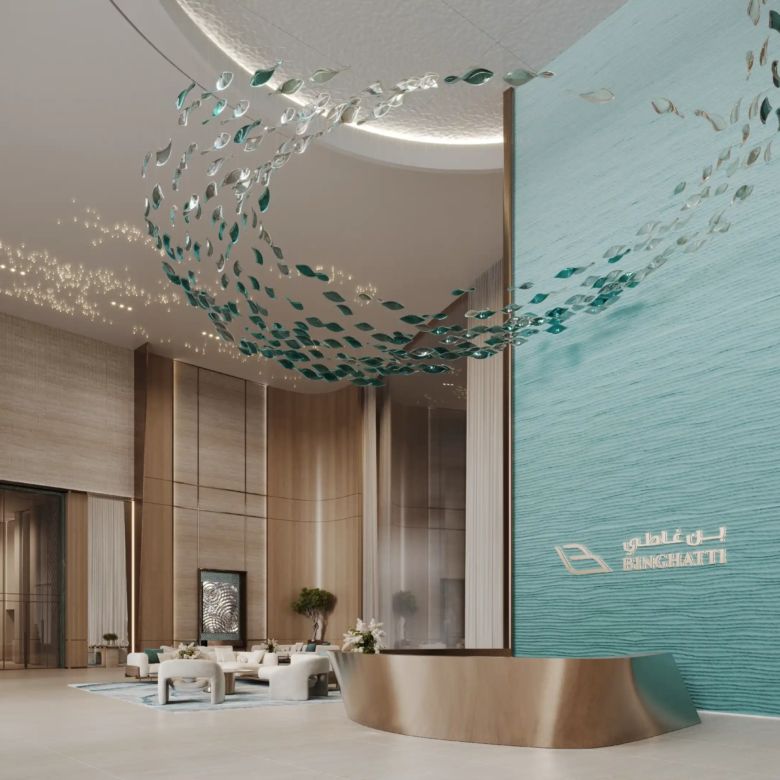 A modern, elegant hotel lobby at Binghatti Aquarise features a turquoise water-inspired feature wall, gold accents, soft seating areas, and a sculptural installation of metallic fish swimming above the reception desk. The space feels bright and spacious.