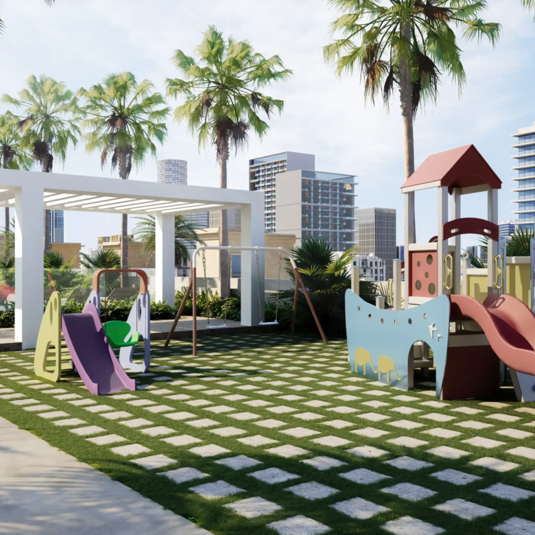 A modern outdoor playground with slides, swings, and climbing equipment on grass, set beneath palm trees and the striking Binghatti Apex and other tall city buildings under a partly cloudy sky.