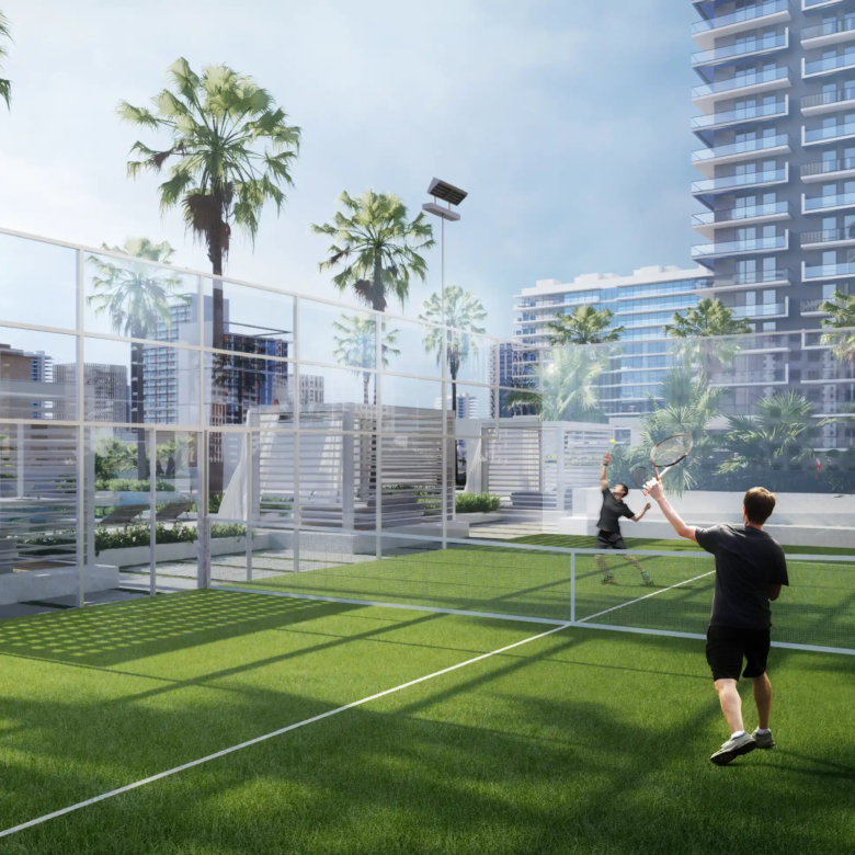 Two people play tennis on an outdoor court surrounded by palm trees and the striking Binghatti Apex high-rise buildings under a clear sky.